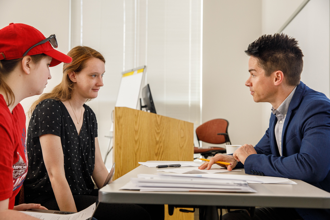 Professor Matt Bruce talking with two students.