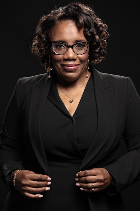 Image of a woman in a black dress and glasses.
