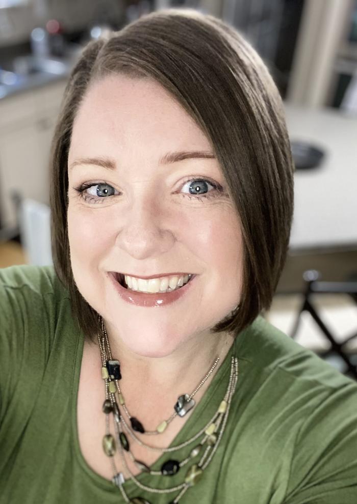 Image of a smiling woman with short brown hair in a green shirt.