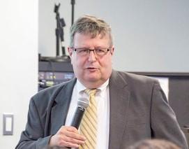 A man in a suit and tie giving a presentation.