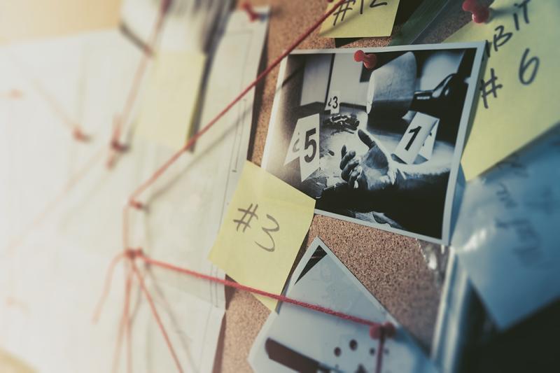 a detective board pinned with photos, post-its, and red string
